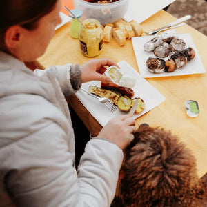 A woman giving a dog food from the table